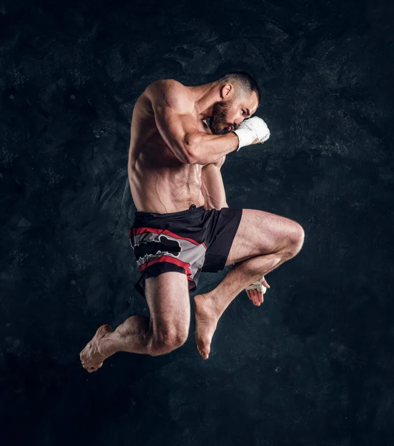 Luchador de MMA en posición de combate dinámico, mostrando técnicas avanzadas de artes marciales mixtas